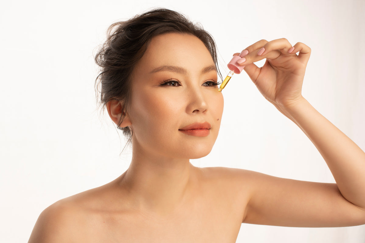 a model is holding bakuchiol booster oil serum onto face